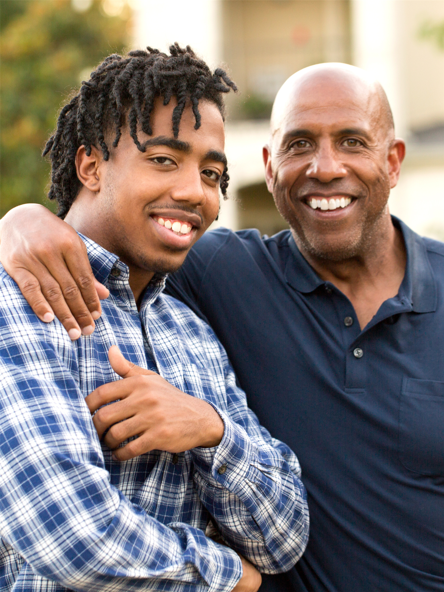 father drapes arm over son's shoulder